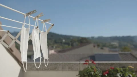 Three white masks hang in a clothesline with a soft wind in the terrace Stock Footage 142234071