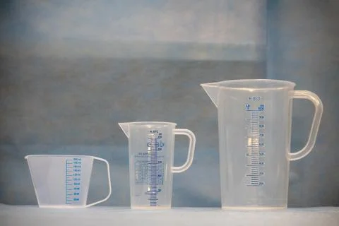Three white measuring cups of different sizes stand next to each other Stock Photos
