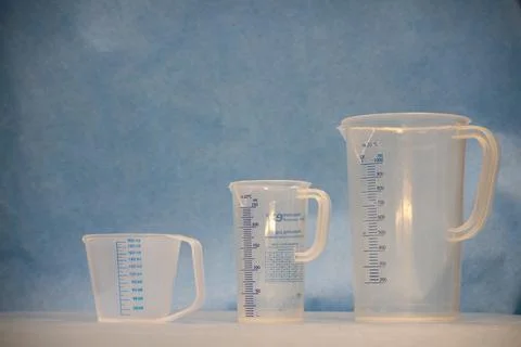 Three white measuring cups of different sizes stand next to each other Stock Photos