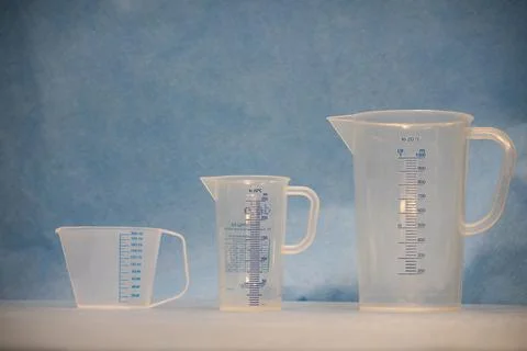 Three white measuring cups of different sizes stand next to each other Stock Photos