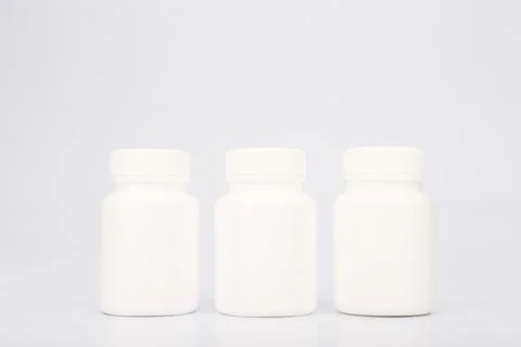 Three white medication bottles in a row on white background Stock Photos