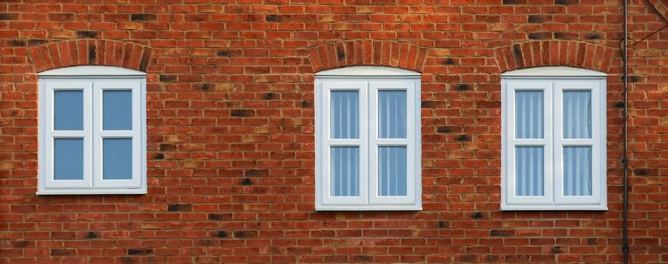 Three white multi pane windows with brick arches on a red brick building fa.. Fotos de archivo