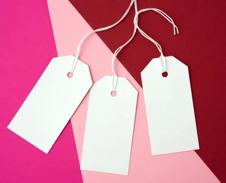 Three white paper rectangular tags on a rope on a colored background Stock Photos