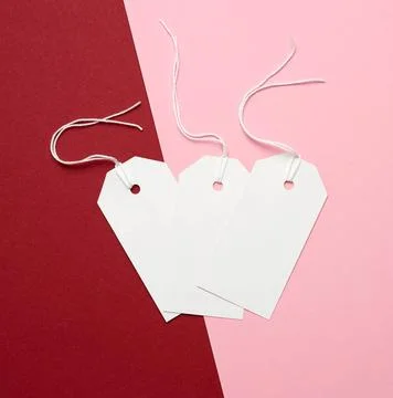 Three white paper rectangular tags on a rope on a colored background three... Stockfoto's