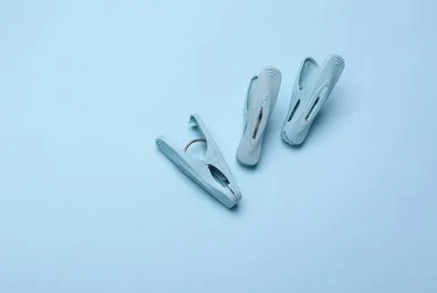 Three white plastic clothespins on light blue background Stock Photos