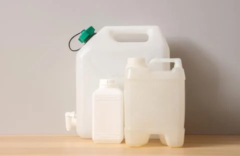 Three white plastic containers with handles on wooden surface against gray wa Stock Photos