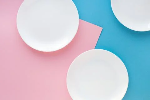 Three white plates on color background. Abstract, top view. Stock Photos