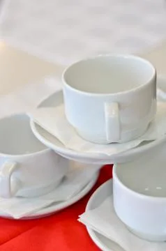 Three white porcelain tea cups and saucers and napkins Stock Photos