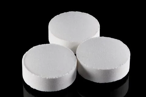 Three white round tablets arranged in a cluster on a reflective black backg.. Stock Photos