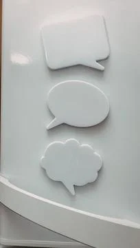 Three white speech bubble icons on a light surface Foto stock