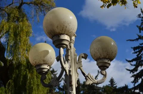 Three white street lights with a blue sky in the background. Stock Photos