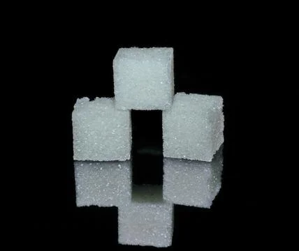 Three white sugar cubes from crystals on black glossy glass Stock Photos