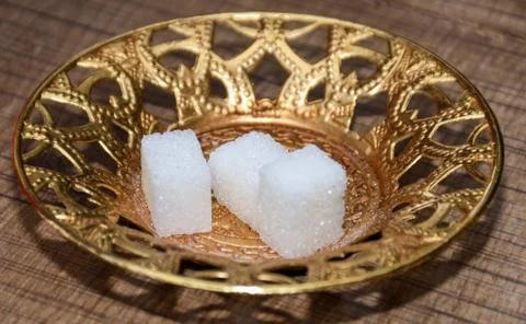 Three white sugar cubes isolated on goden turkish plate, for morning coffee s Stock Photos