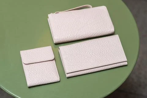 Three white wallets on the green table Stock Photos