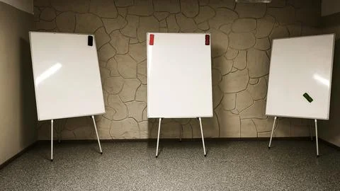 Three whiteboard stands in classroom with blank surfaces and colorful clips. Fotos de archivo
