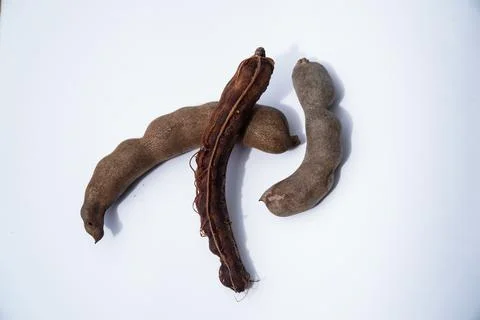 Three Whole and Partially Opened Tamarind Pods on a Clean White Background Stock Photos