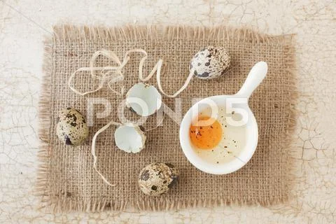 Three whole quail's eggs with a cracked open egg and shells Stock Photos
