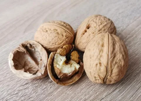 Three whole walnuts and one cracked walnut Stock Photos