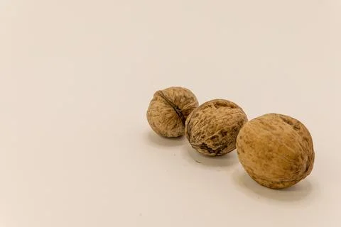 Three whole walnuts are displayed on a plain light surface, ready for snackin Stock-Fotos