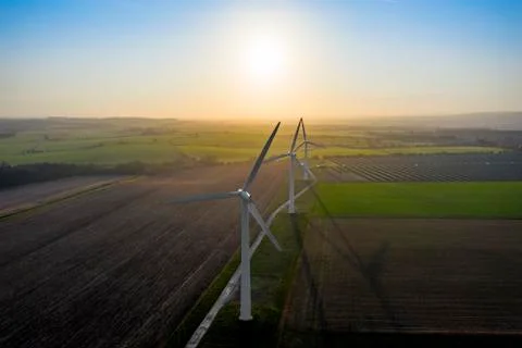 Three wind turbines with a dramatic sky at sunrise aerial, England Фото