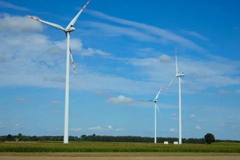 Three wind turbines generate renewable energy under a clear blue sky in a r.. Foto stock