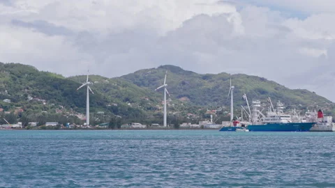 Three wind turbines spinning in the wind at the base of a hill Stock Footage 236554162