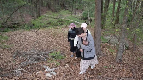 Three women climb a leaf-covered forest path 스톡 동영상 343705744