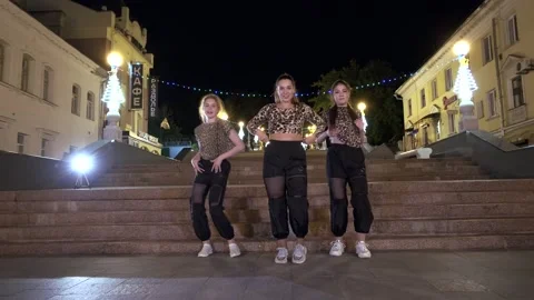 Three women dance in front of huge stone staircase in night. Gimbal shot Stock Footage 134909751