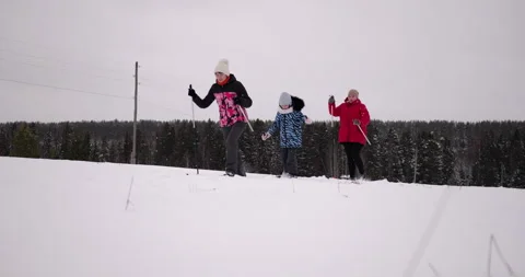 Three women of different ages skiing enthusiastically across snowy field toward Stock Footage 319792007