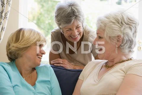 Three women in living room talking and smiling Stock-Fotos