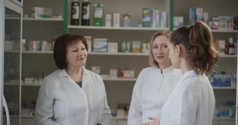 Three women pharmacyft in uniform are standing in the pharmacy and discussing im Stock Footage 124106966