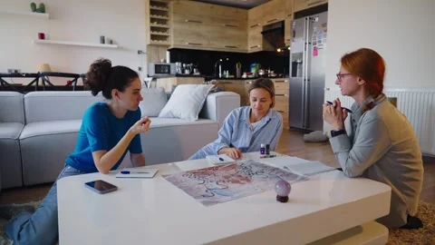 Three women play the ancient Indian board game Leela in a cozy living room Stock Footage 307756608