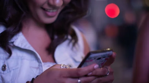 Three women stand around using their phones in the city at night, in slow motion Stock Footage 67758802