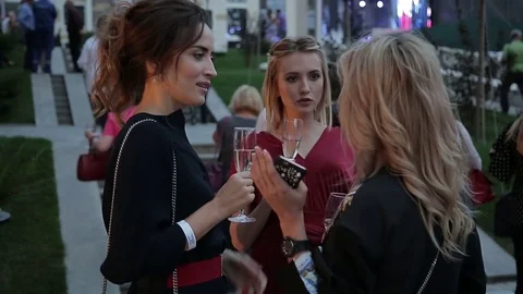 Three Women talk, hold a Glasses of white Wine in their Hands at a Party Stock Footage 80367266