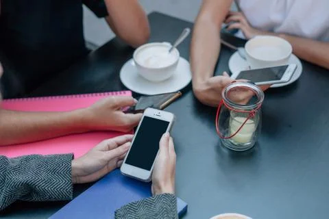 Three women's hands are using smartphones at the coffe table. Stock Photos