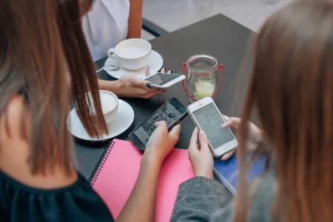 Three women's hands are using smartphones at the coffe table. Stock Photos