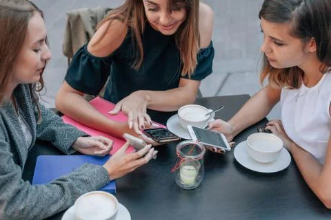Three women's hands are using smartphones at the coffe table. Stock Photos