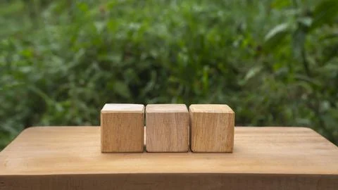Three Wooden Cubes on Rustic Table with Green Nature Background Stock Photos