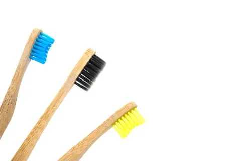 Three wooden toothbrushes with multi-colored natural bristles isolated on whi Stock Photos