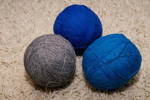 Three woolen balls of blue, blue and gray colors lie on a white background Stock Photos