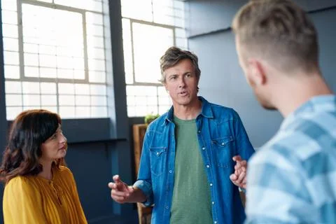 Three work colleagues having a discussion together in an office Stock Photos