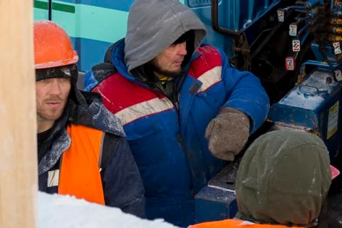 Three workers are talking about a hydraulic lift 写真素材