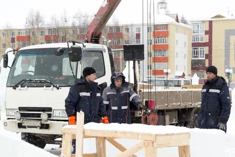 Three workers on the installation of ice blocks for the ice town 스톡 사진