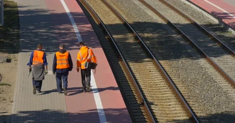 Three Workers Men in Orange Workwear are Walking Away along the Empty Railroad Stock Footage 55300873