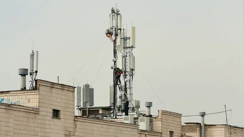 Three workers set up a huge antenna on the roof of a high-rise building Video stock 73664650