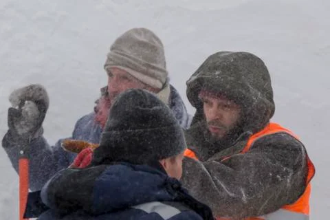Three workers in a snowstorm during snow removal 스톡 사진