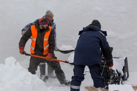 Three workers in a snowstorm during snow removal 写真素材