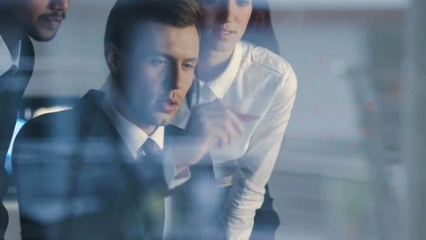 The three workers stand over the glass board and discuss graph Stock Footage 71162884