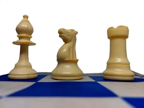 Three worn plastic chess pieces (bishop, knight, rook) on white-blue board Stock Photos
