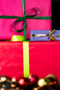 Three wrapped gifts, bowknots, spheres and glitters. Stock Photos